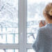 Woman standing by a window during a snowy Canadian winter